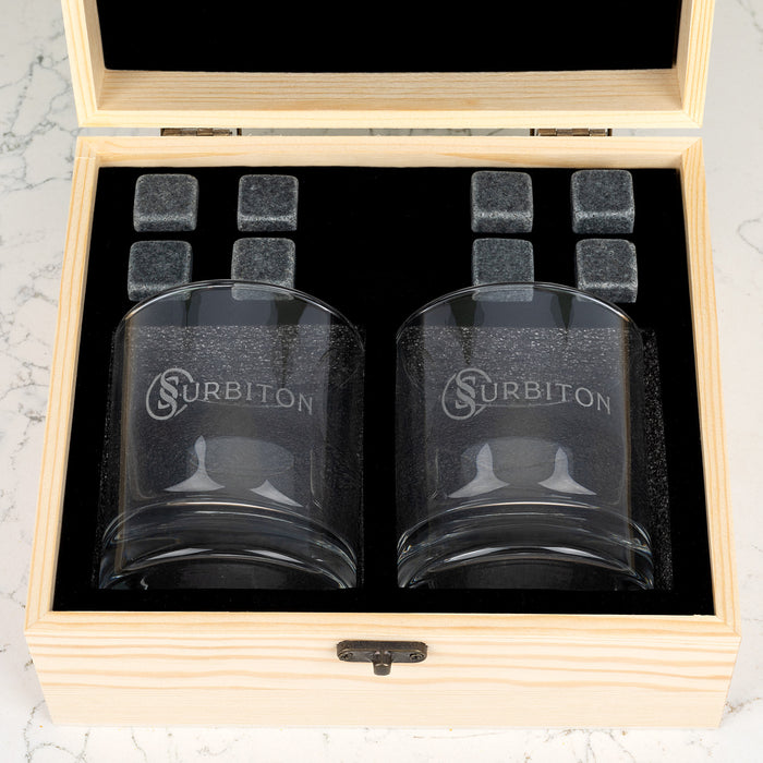 Wooden whiskey gift box open to reveal personalised glasses and reusable whiskey stones for corporate gifting.