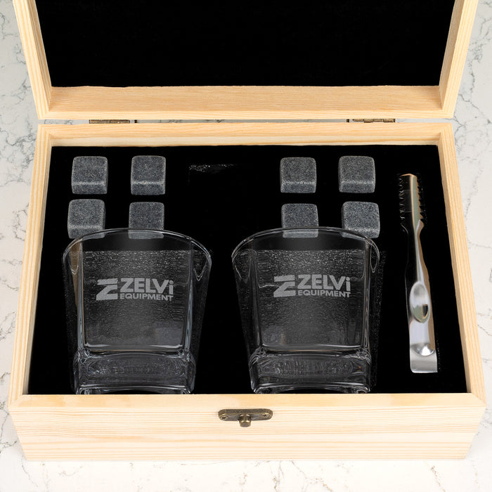 Branded whiskey gift set with company logo engraving on premium glassware, complete with reusable stones and accessories for client gifting.