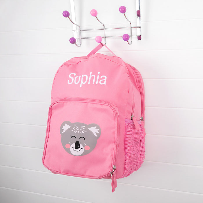Pink personalised kids backpack with embroidered child's name and smiling koala face print.