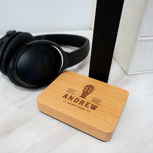 Custom wooden headphone stand keeping gaming headphones organised on a desk beside a laptop.