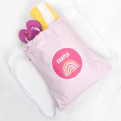 Personalised pink kids swim bag with rainbow design and child's name printed on front.