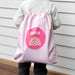 Child wearing pink drawstring swim bag with rainbow print and personalised name.