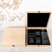 Custom wedding gift set with engraved decanter, matching glasses, and velvet bag of whiskey stones in a rustic wooden box