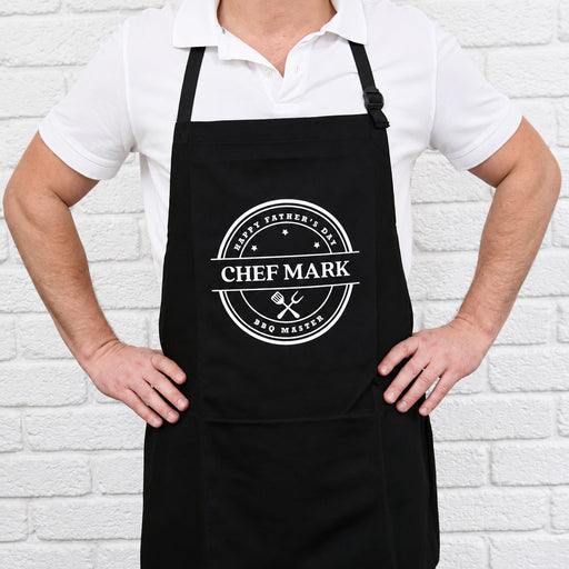 Personalised black BBQ apron with bold white print and custom name, a practical gift for Dad, Grandad or the BBQ King.