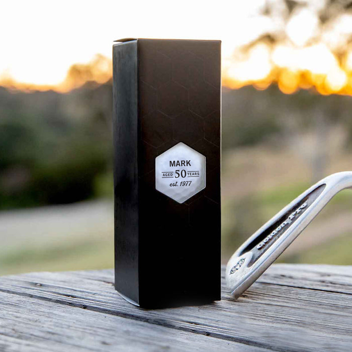 Set of three custom golf balls with initials, presented in a sleek black box – ideal for golf-themed birthday gifting.